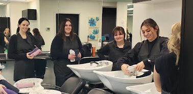 Smiling students of Esteem Academy of Beauty preparing their student salon hair station. 